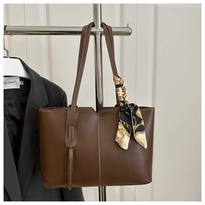Detail of brown tote bag with white contrast stitching and a printed silk scarf handle