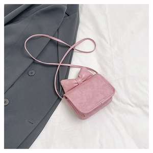 Detailed view of a mini pink crossbody bag featuring a large 3D leather bow accent