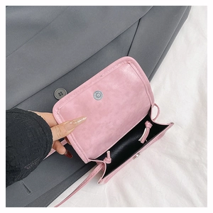 Detail view of pink mini crossbody bag with magnetic snap closure and black interior lining