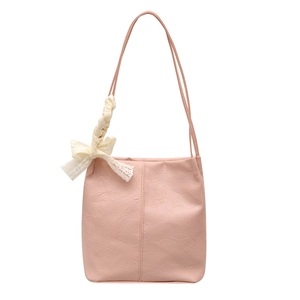 Pink minimalist tote bag with thin straps and a white lace bow charm on plain background