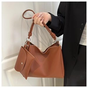 Brown leather tote bag featuring a knotted handle detail and matching small pouch
