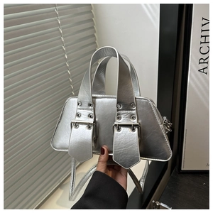 Macro detail of silver trapezoid handbag featuring wide handles and large metal buckles