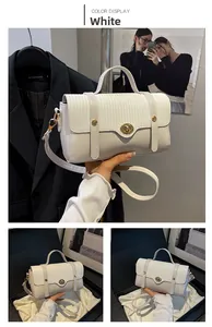 Detail of white patchwork handbag featuring woven flap, golden turn-lock, and leather strap