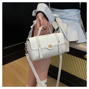 Detail of white woven flap handbag featuring gold metal turn-lock and adjustable strap