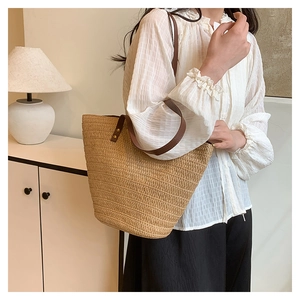 Détail du sac cabas en paille montrant la texture des fibres et les anses en cuir