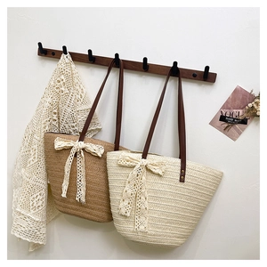 Detail of straw tote bags featuring delicate lace bows and premium brown leather straps