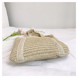 Detailed close-up of beige woven straw tote bag with mesh hollow texture and tassel