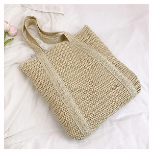 Detailed view of beige straw woven tote bag featuring vertical stripes and wide handles