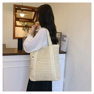 Close-up of woven straw tote bag texture and fringe tassel detail in cream white