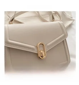 Detail van de crèmekleurige leren tas met gouden ovale sluiting en kiezelstructuur