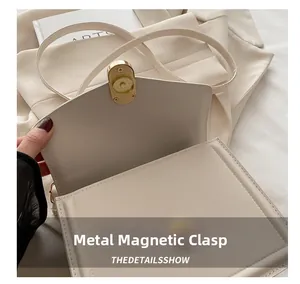 Detail van de gouden magneetsluiting op de elegante ivoren lederen crossbody handtas