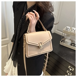 Detail van een beige lederen handtas met een gouden draaislot en een bovenhandgreep