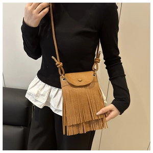 Detailed close-up of a brown crossbody bag featuring long fringes and textured finish