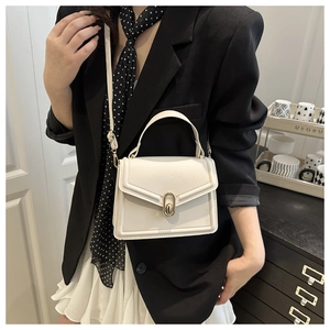 Detail of a white crossbody handbag with gold oval twist lock and sleek stitching