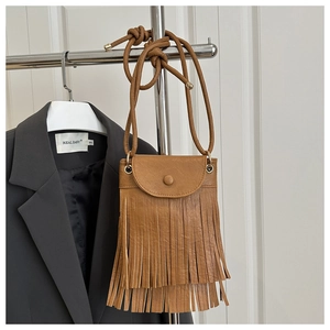Détail d'un petit sac bandoulière marron en similicuir avec franges et bandoulière fine