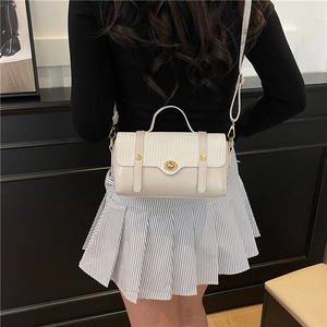 Minimalist cream white crossbody bag with woven texture and gold twist lock in hand