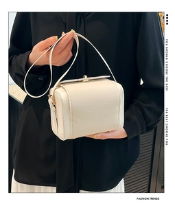 Detail showing creamy beige leather texture and gold metal buckle on crossbody bag