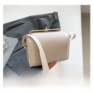 Detail of cream crossbody bag featuring a golden twist lock and lychee grain leather