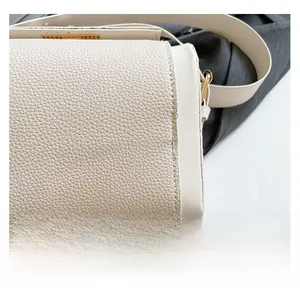 Close-up of cream lychee grain leather bag showing fine texture and precision stitching