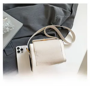 Compact lychee grain crossbody bag shown next to a smartphone for size comparison