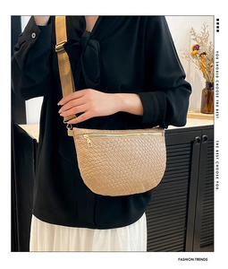 Detail of light khaki woven crescent bag with gold zipper and stylish wide strap