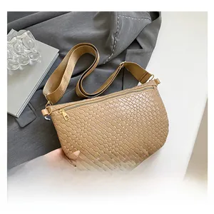 Close-up of khaki woven dumpling bag with wide fabric strap and gold zipper detail