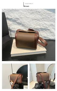 Detail of a brown leather box bag featuring contrast textures and gold hardware buckle