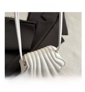 Detailed side view of white shell-shaped shoulder bag featuring pleated texture and stitching
