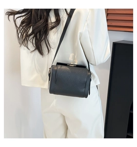 Modern black crossbody bag with gold buckle shown on a white blazer outfit