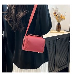 Detail of red lychee leather crossbody bag with gold metal feet and wide strap