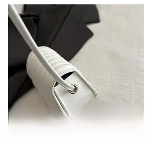 Detailed side view of white leather crossbody bag with vertical quilted stripes