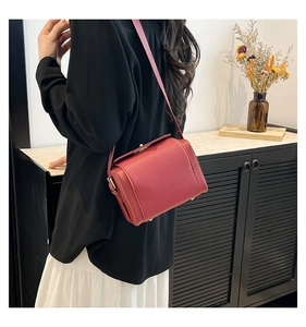Detail of red leather crossbody bag featuring a gold metal buckle and clear skin texture