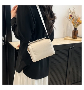 Close-up of cream textured leather crossbody bag showing golden protective bottom feet