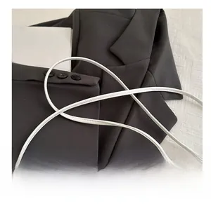 Close-up of slim round shoulder strap on white leather shell bag with quilted texture