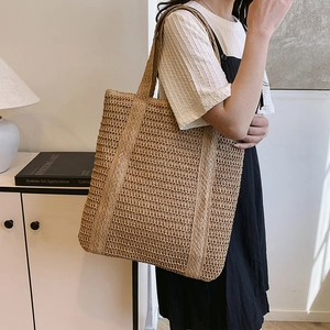 Minimalist straw woven tote bag for beach vacations with large capacity shown on shoulder