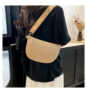 Détail du sac de poitrine beige matelassé avec large bandoulière sur un modèle