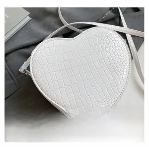 Detail shot of heart-shaped white crossbody bag with premium crocodile embossed texture