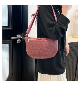 Detail of burgundy woven crescent bag showing premium leather texture and wide strap
