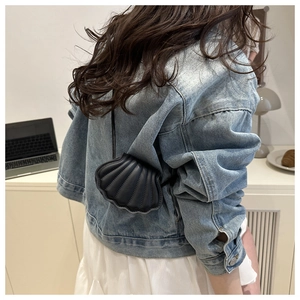Detail of creative black shell shaped mini crossbody bag paired with denim jacket