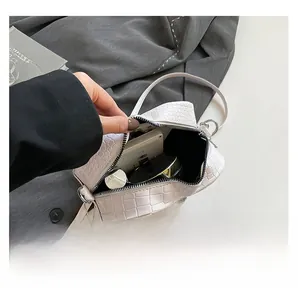 Detail view of white croc-embossed crossbody bag showing internal storage capacity