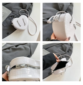 Detail of white heart-shaped bag with crocodile pattern and silver chain accents