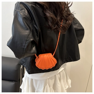Detail of an orange shell-shaped mini crossbody bag featuring textured 3D vertical stripes