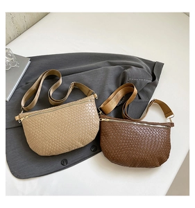Detail of woven crescent crossbody bags in beige and brown with wide nylon straps