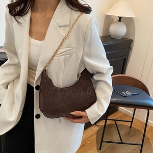 Deep brown snake-print hobo bag with gold chain strap worn by a model in white blazer
