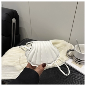 Close-up of shell-shaped mini crossbody bag with cream white curved stitching detail