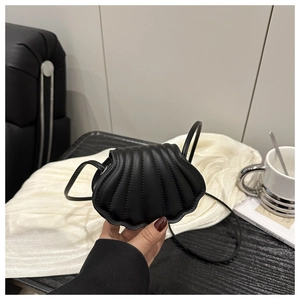 Detailed close-up of a black shell-shaped mini crossbody bag with vertical stitching