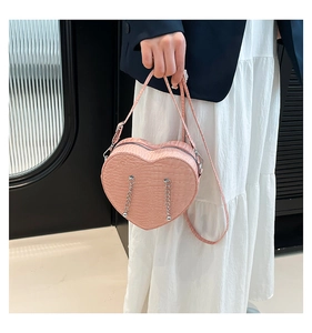 Detailed shot of pink heart-shaped bag with crocodile texture and silver chain accents