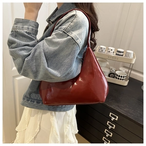 Detail of glossy vintage red leather underarm bag with a sleek crescent moon shape