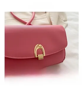 Close-up of pink leather handbag featuring a signature golden U-shaped metal buckle
