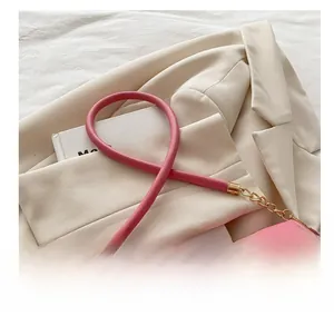 Pink leather shoulder bag detail with thick cylindrical handle and gold metal chain link